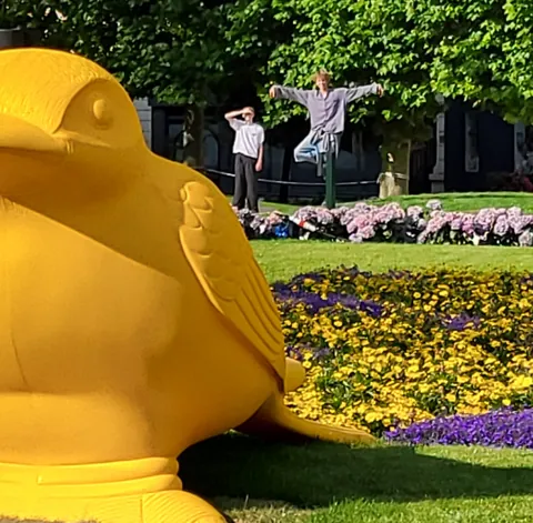Un énorme oiseau jaune dans un jardin fleuri