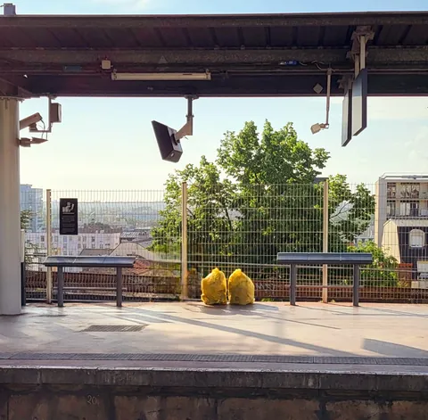 Deux sacs jaunes posés sur un banc de quai de gare