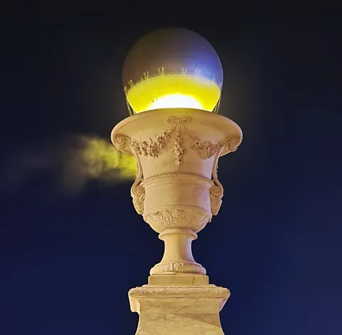 Un réverbère en forme de vase éclairé la nuit