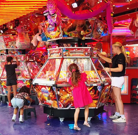 Des enfants autour d’une machine à sous de fête foraine