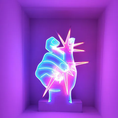 Œuvre en néon d’une main dans un décor rose