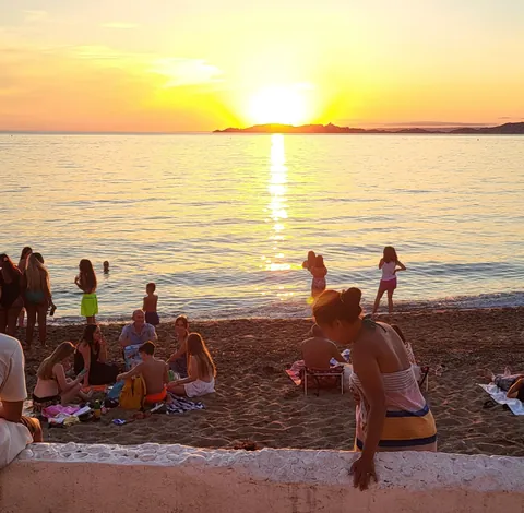 Des baigneurs sur la plage au coucher du soleil