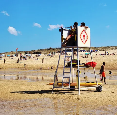 Une chaise de maître-nageur sur roues au milieu d’une plage