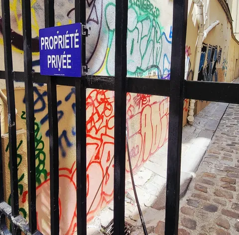 Une grille « Propriété privée » devant un mur entièrement tagué