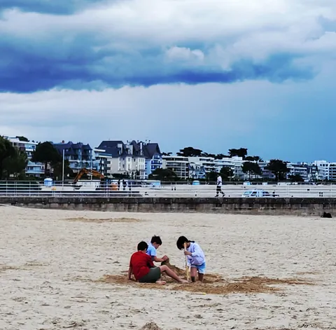 Deux enfants qui jouent dans le sable devant une station balnéaire