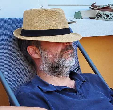 Un homme endormi sur un transat, le chapeau sur les yeux