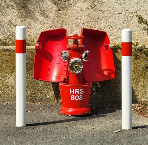 Une borne à incendie rouge entre deux poteaux, comme un éléphanteau