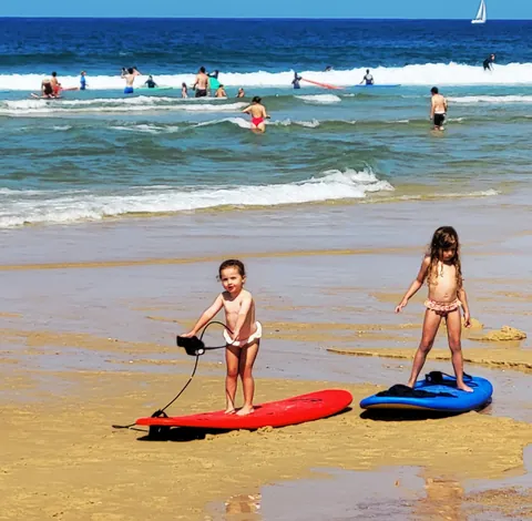 Deux petites filles debout sur des planches de surf au bord de l’eau
