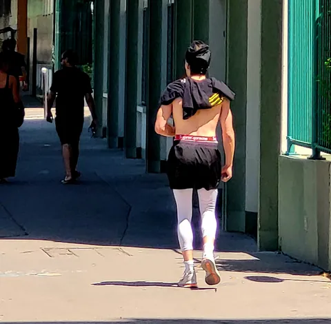 Un homme torse nu en short noir et collants blancs, de dos