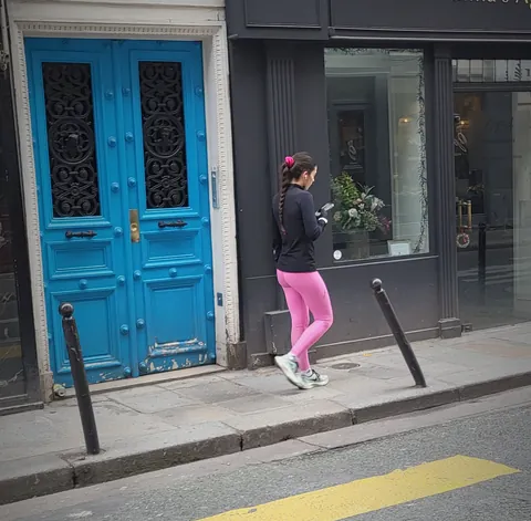 Une joggeuse en legging rose devant une porte bleue