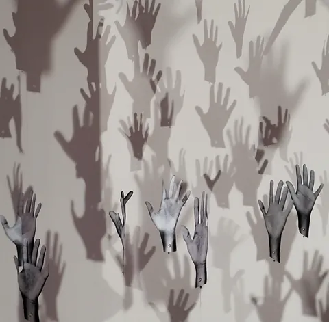Des mains peintes et leurs ombres sur un mur