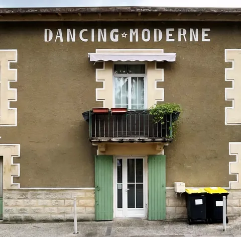 La façade « Dancing Moderne » d’une vieille maison, poubelles jaunes devant la porte