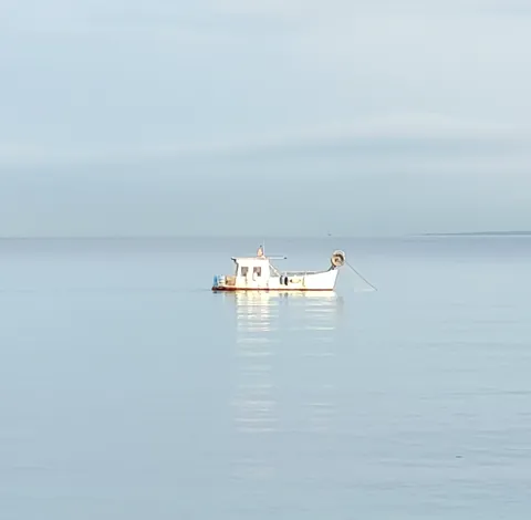 Une petite barque seule sur une mer d’huile