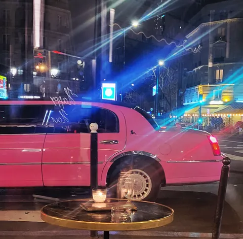 Une limousine rose garée dans une rue, la nuit
