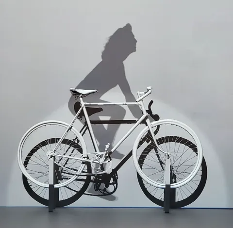 Un vélo blanc devant l’ombre d’une cycliste peinte sur un mur