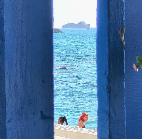 Un paquebot au large, aperçu entre deux poteaux bleus
