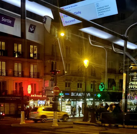 Un carrefour parisien la nuit, enseignes lumineuses
