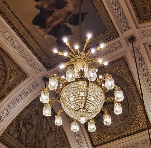 Un lustre de cristal suspendu à un plafond peint et doré