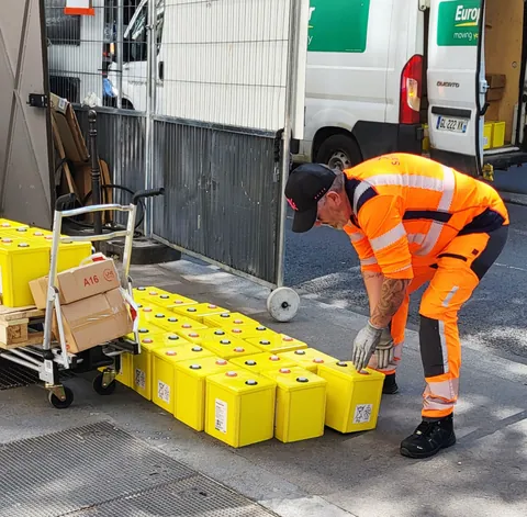 Un ouvrier en orange qui empile des caisses jaunes
