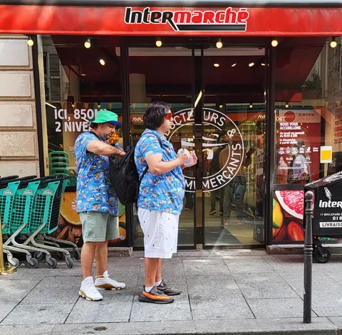 Deux hommes en chemises hawaïennes identiques devant un Intermarché