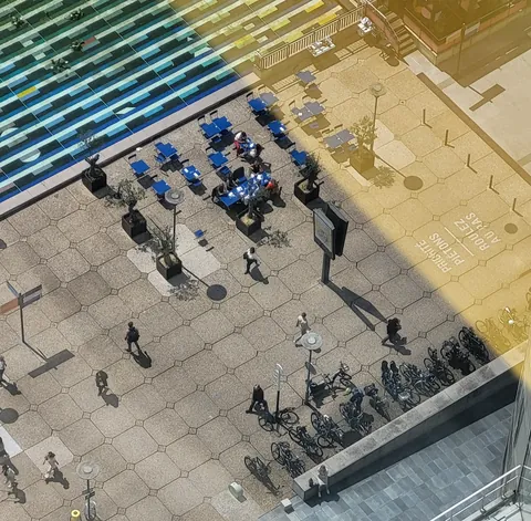 Une place vue d’en haut, tables bleues et vélos minuscules