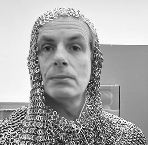 Un homme coiffé d’une cagoule en cotte de mailles, en noir et blanc