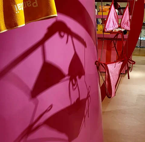 Le reflet d’un bikini rose sur une paroi