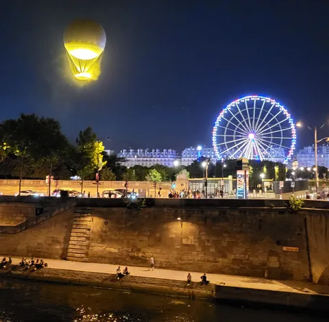 Une grande roue illuminée et un ballon jaune dans la nuit
