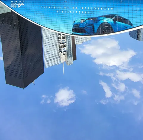 Une tour et une voiture bleue qui se reflètent à l’envers dans le ciel