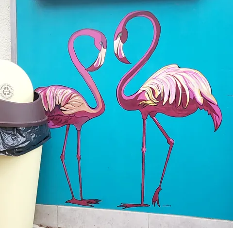 Deux flamants roses peints sur un mur turquoise