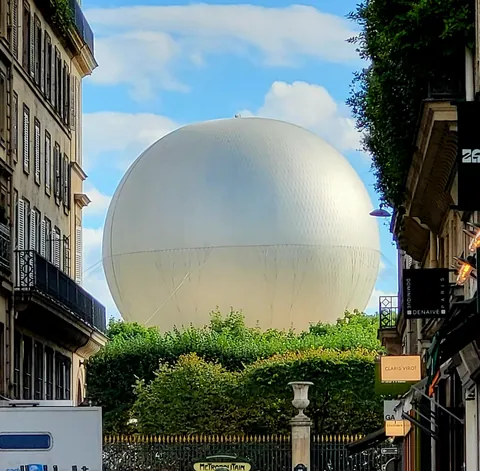 Une grande sphère blanche au bout d’une rue, au-dessus des arbres