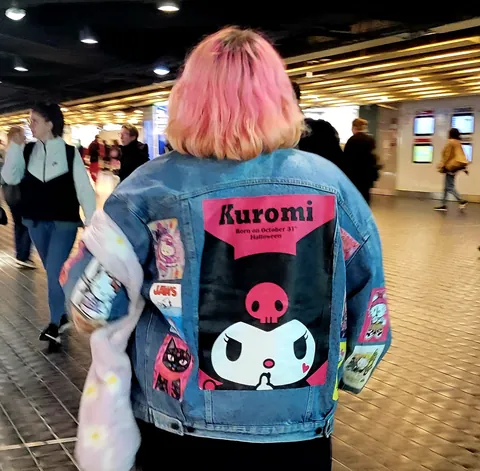 Une veste en jean Kuromi et des cheveux roses, de dos