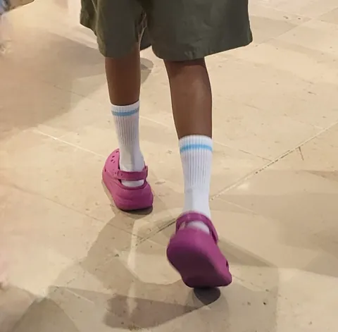 Des pieds en Crocs roses et chaussettes blanches