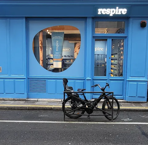 Une boutique bleue « Respire » avec un vélo garé devant