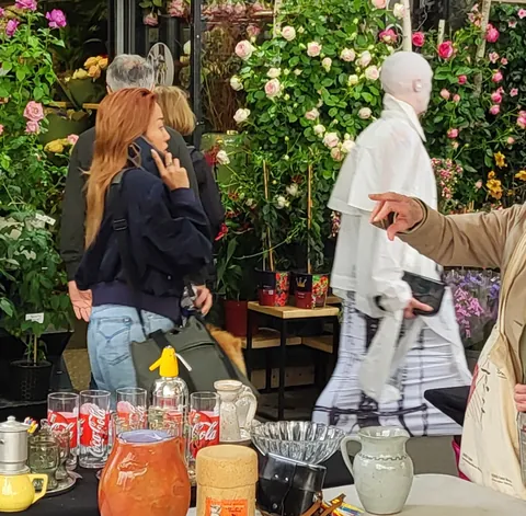 Un mannequin blanc entre des étals de fleurs et de bocaux