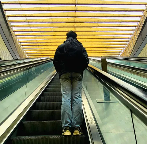 Un homme de dos sur un tapis roulant sous un plafond jaune