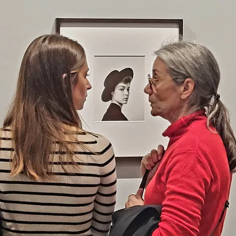 Deux femmes qui discutent devant un portrait photographique dans une exposition