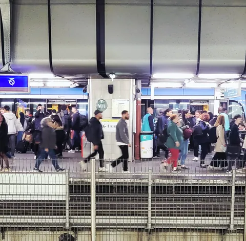 Une foule de voyageurs sur le quai d’une gare, vue depuis une passerelle
