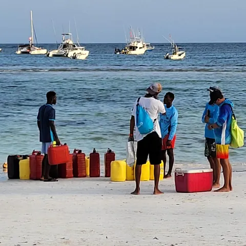Des hommes sur une plage avec des bidons d’essence pour bateaux