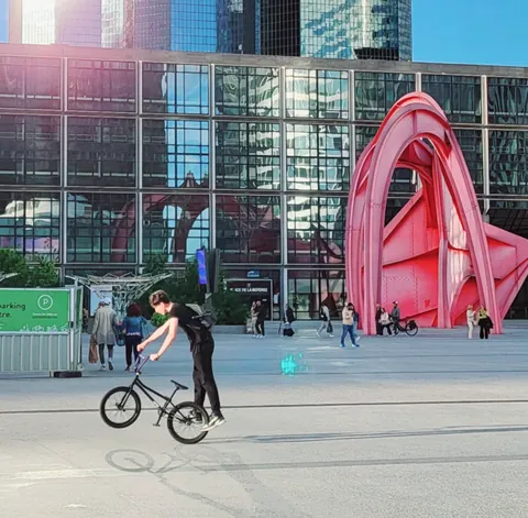Un cycliste qui saute devant le stabile rouge de Calder à la Défense