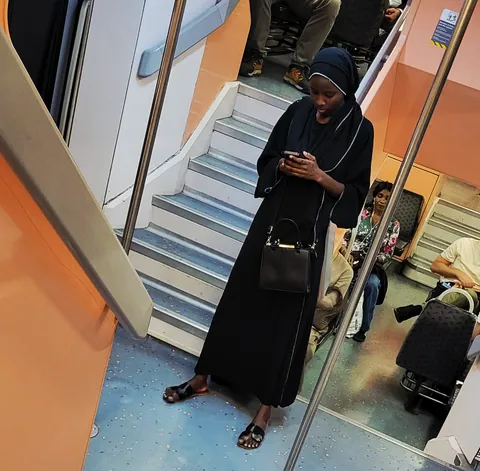 Une religieuse en noir qui regarde son téléphone dans un train