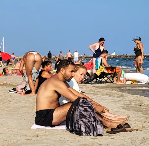 Un homme torse nu assis au soleil sur une plage