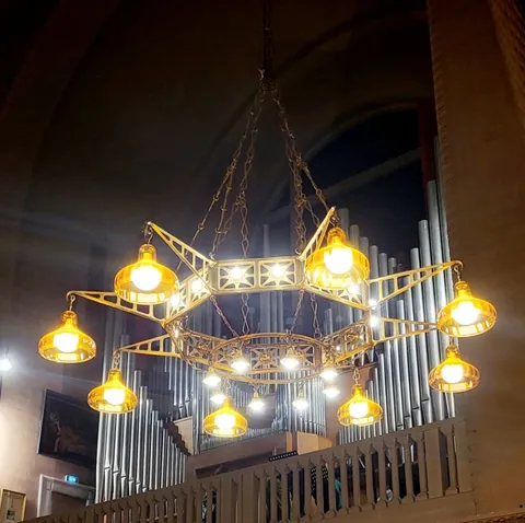 Un lustre en forme d’étoile garni d’ampoules allumées, devant les tuyaux d’un orgue