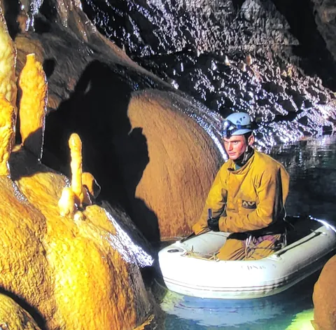 Un homme dans une barque gonflable au fond d’une grotte
