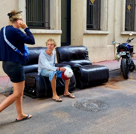 Un homme assis sur un canapé en cuir posé sur le trottoir