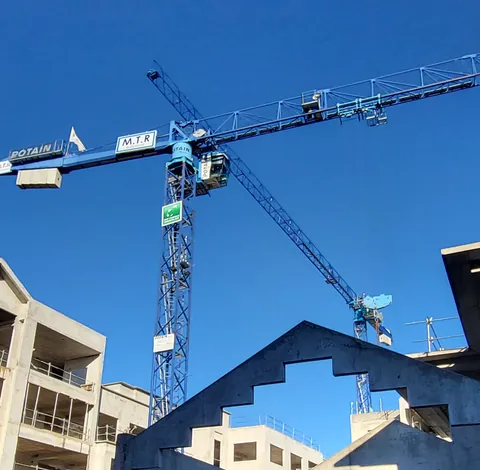 Une grue sur fond de ciel bleu et d’immeubles