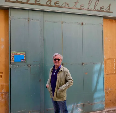 Un homme devant un grand portail vert-de-gris