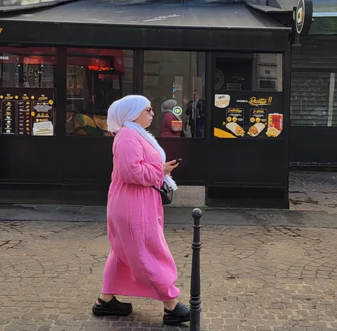 Une femme en djellaba rose devant un kebab