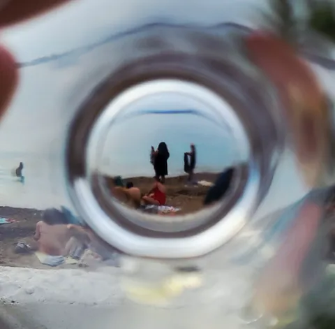 La plage vue à travers le fond d’un verre