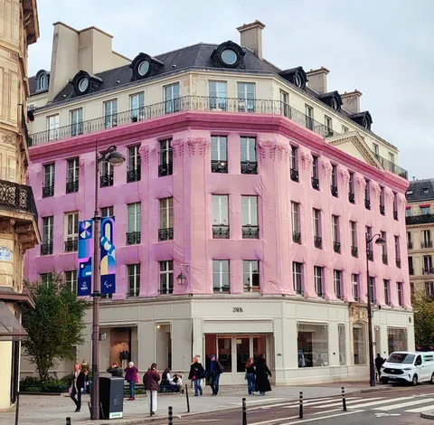 Un immeuble rose au coin d’une rue